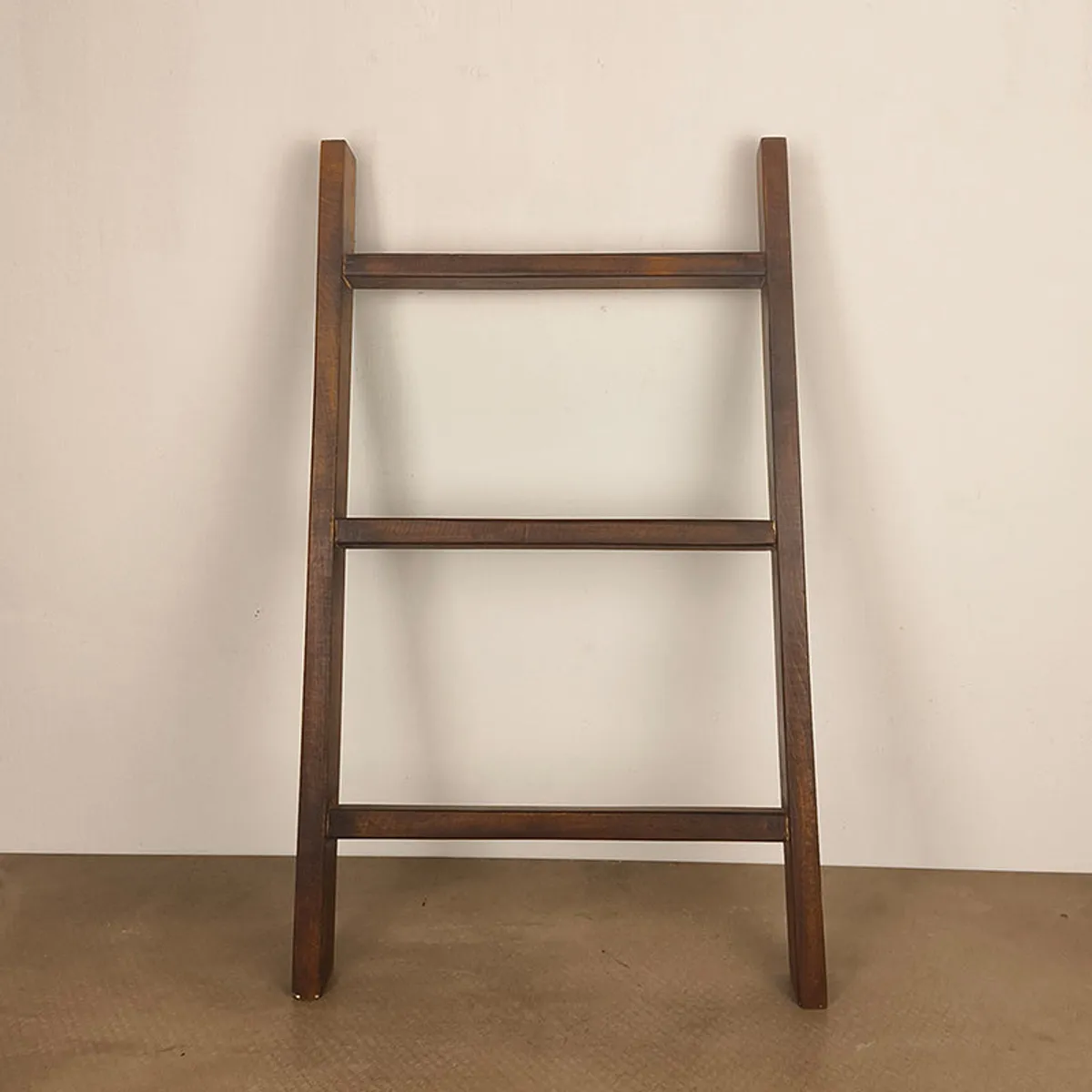 Front view of a brown wooden ladder-style rack against a plain backdrop