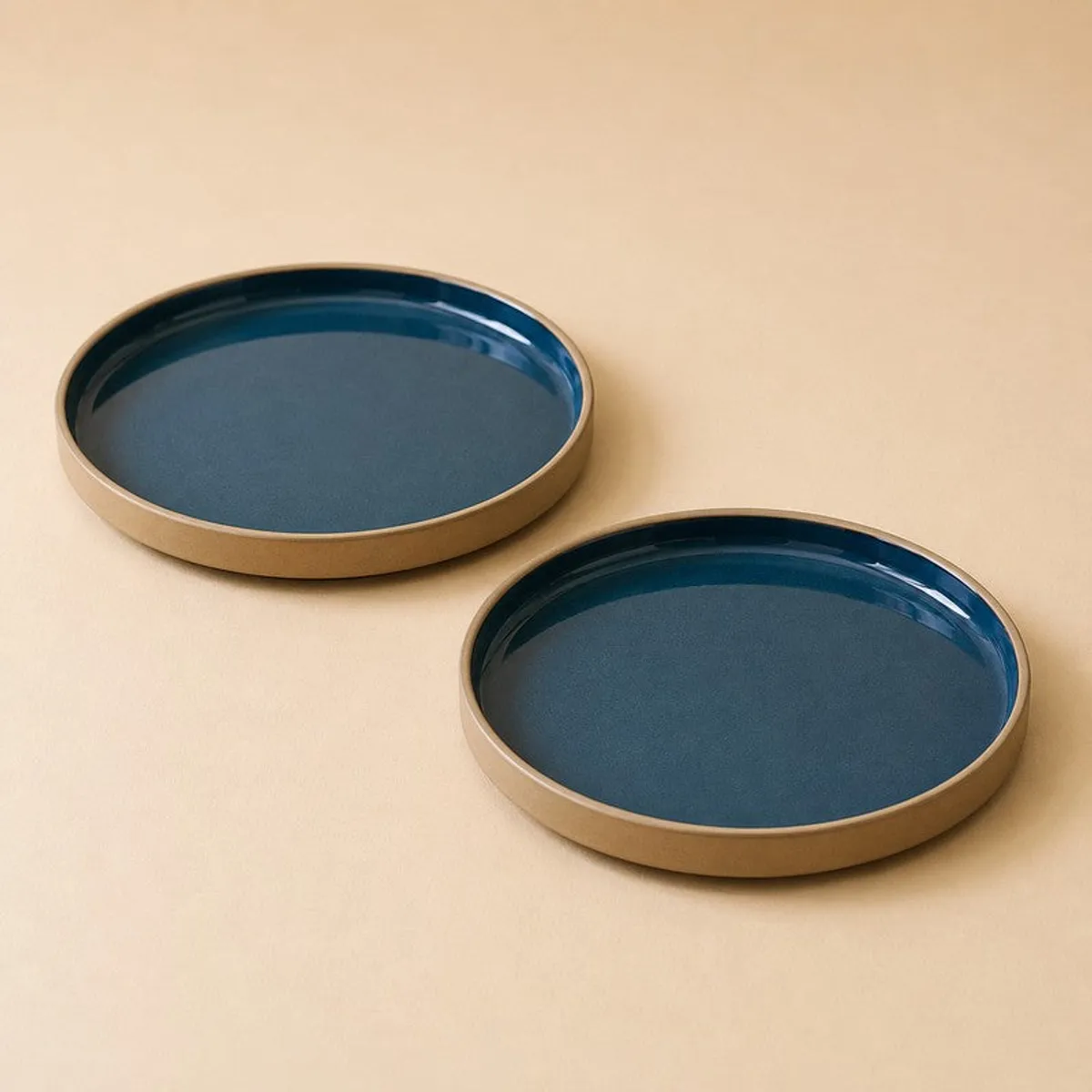 Two blue ceramic plates arranged diagonally on a neutral background
