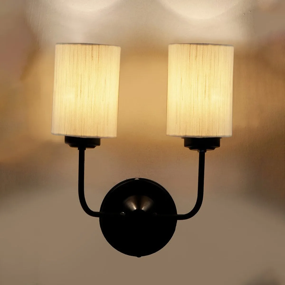 Close view of lit twin wall lamp with black base and white shades