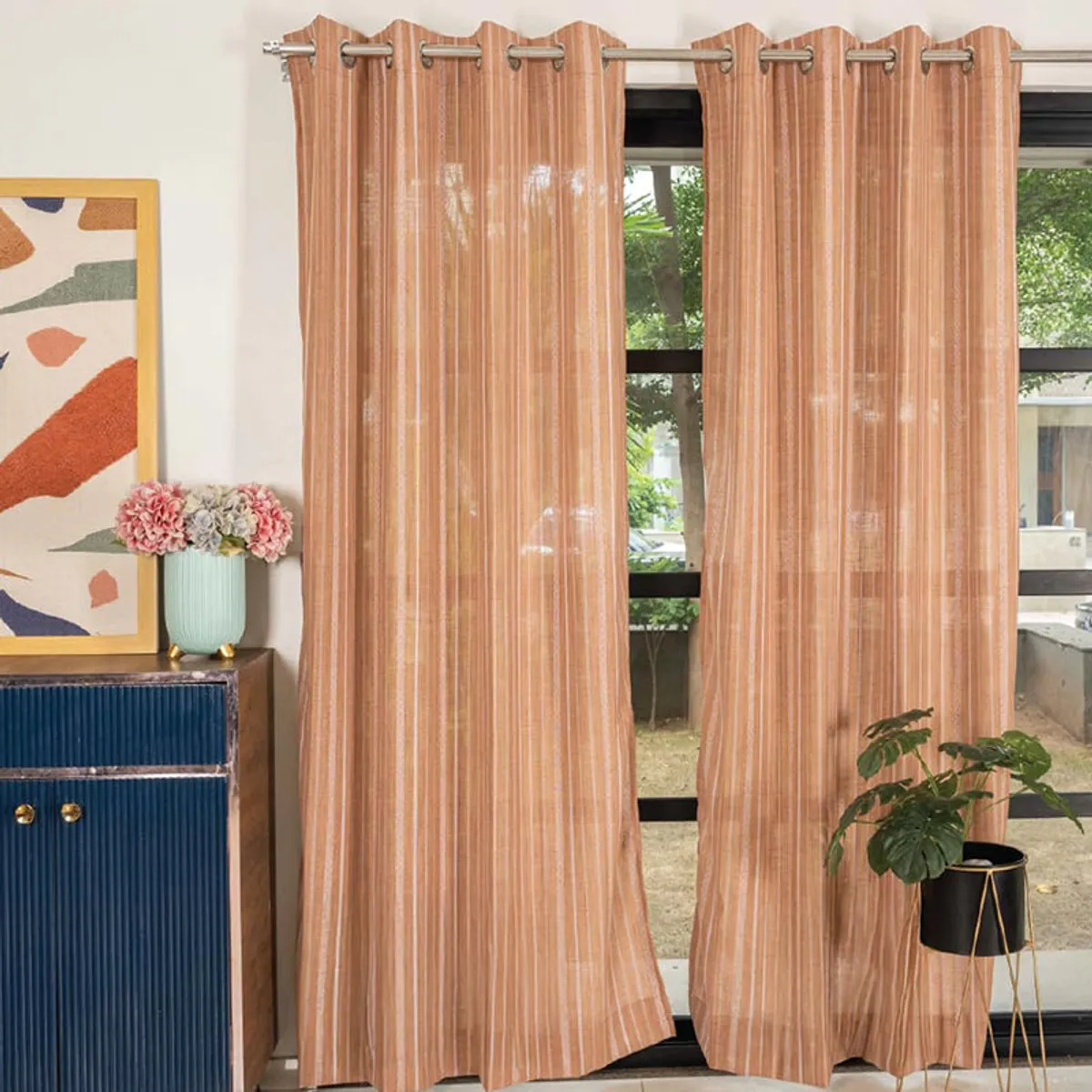 Muddy pink striped curtains hung across a large window in a stylish living room