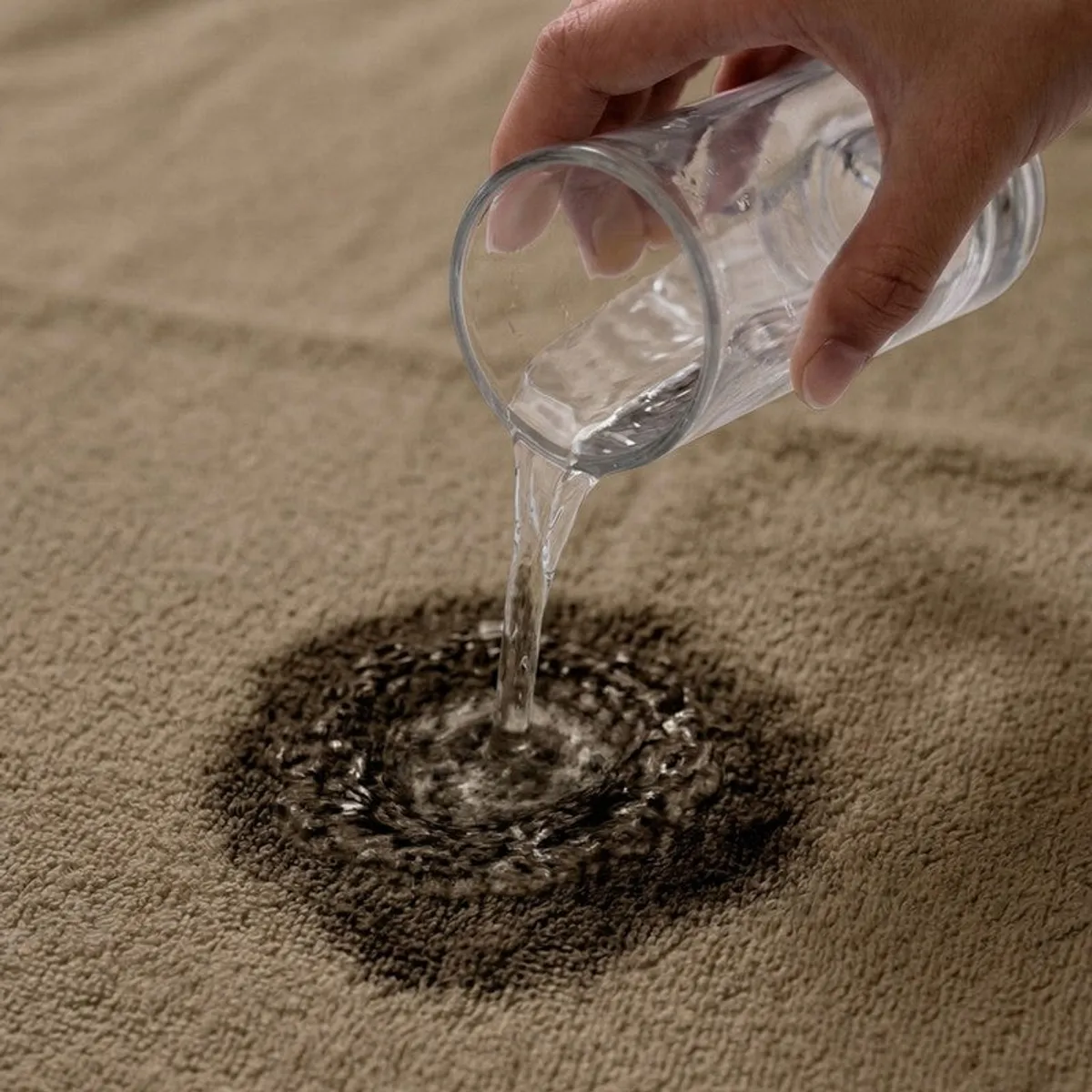 Close-up of water being poured onto the absorbent brown towel.