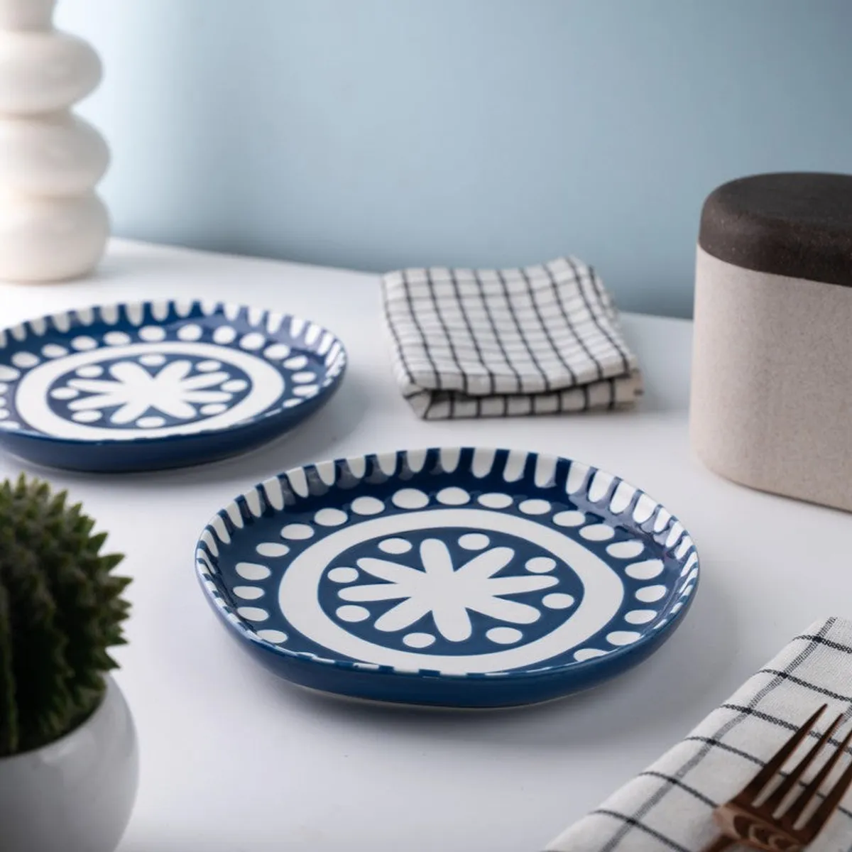 Two blue and white patterned plates styled with folded napkins and tableware