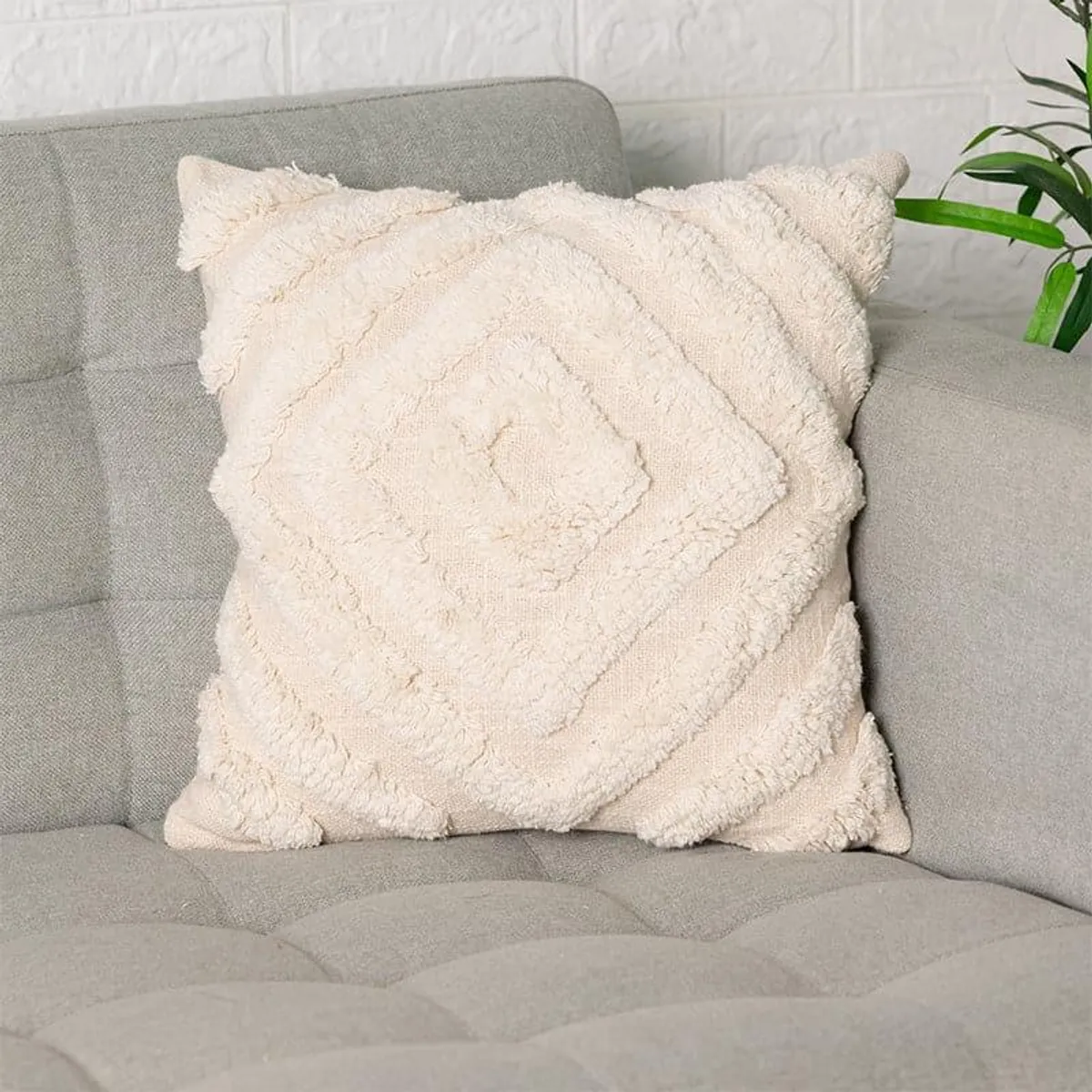 Single ivory cushion cover showing its raised diamond tufted pattern on a sofa