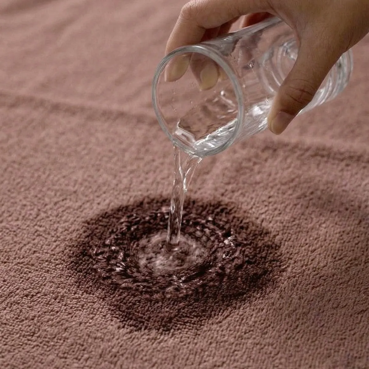 Water being poured onto the soft textured surface of a brown bath towel