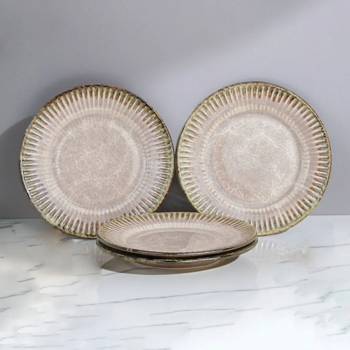 Four round ceramic quarter plates displayed against a grey backdrop