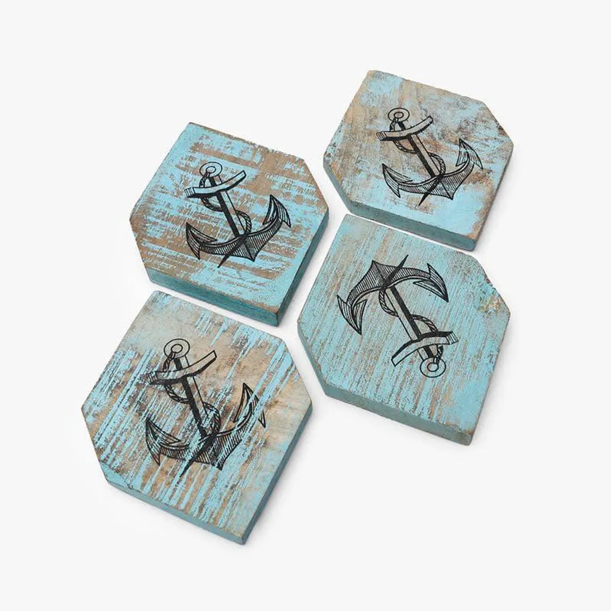 Four blue wooden coasters with anchor designs laid out on white