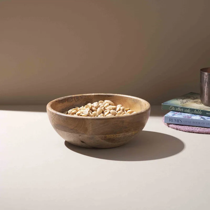 Mango wood serving bowl filled with snacks on a tabletop