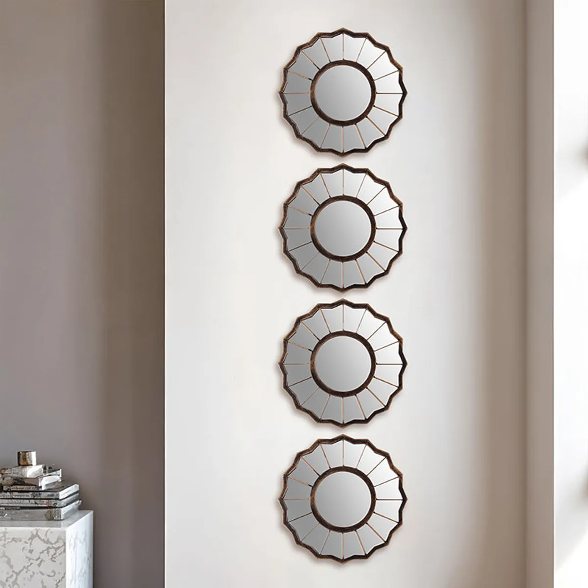 Four round copper-toned wall mirrors arranged vertically on a light wall