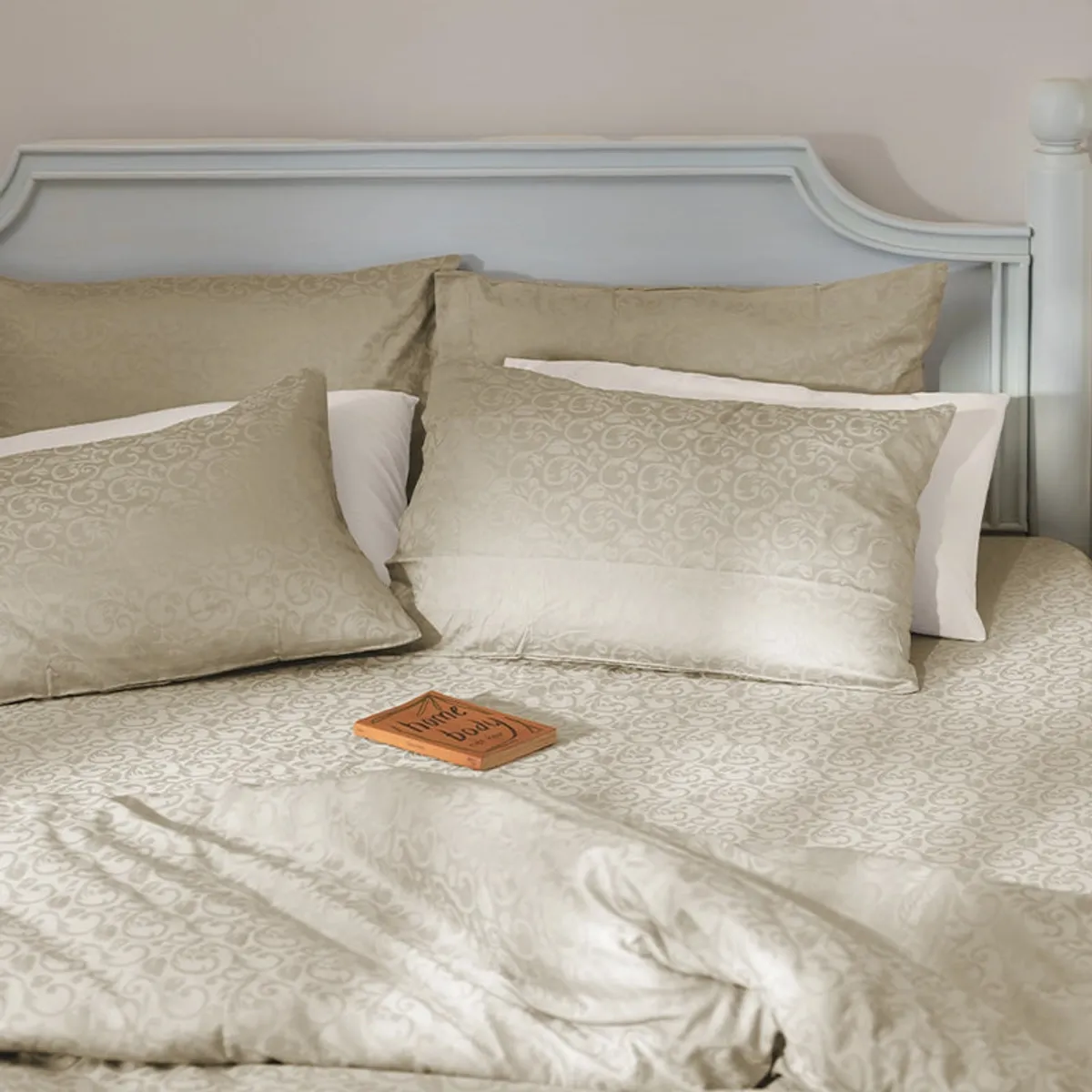 Beige floral bedsheet styled across a bed with layered pillows