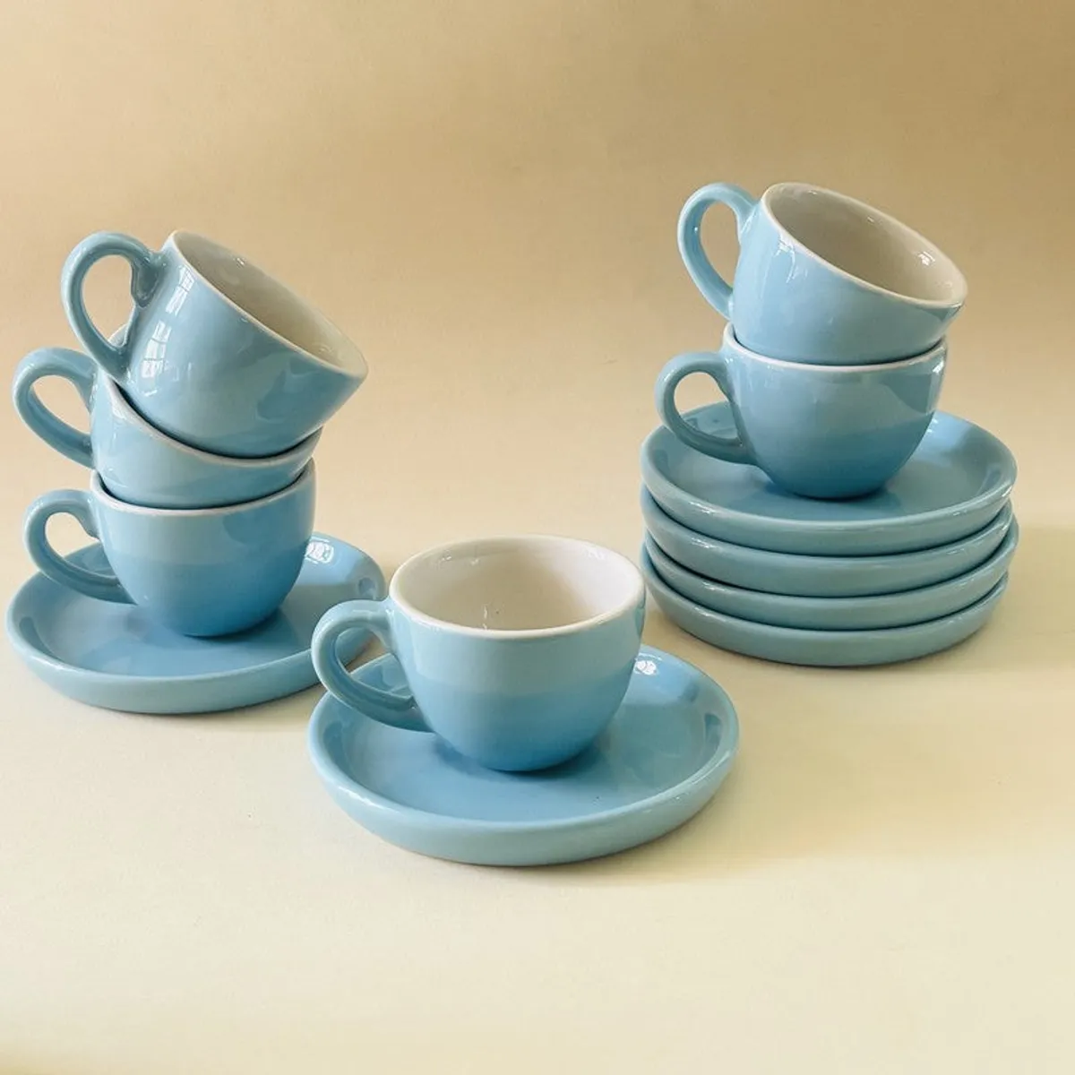 Glossy blue cups and saucers arranged in stacks with one cup in front