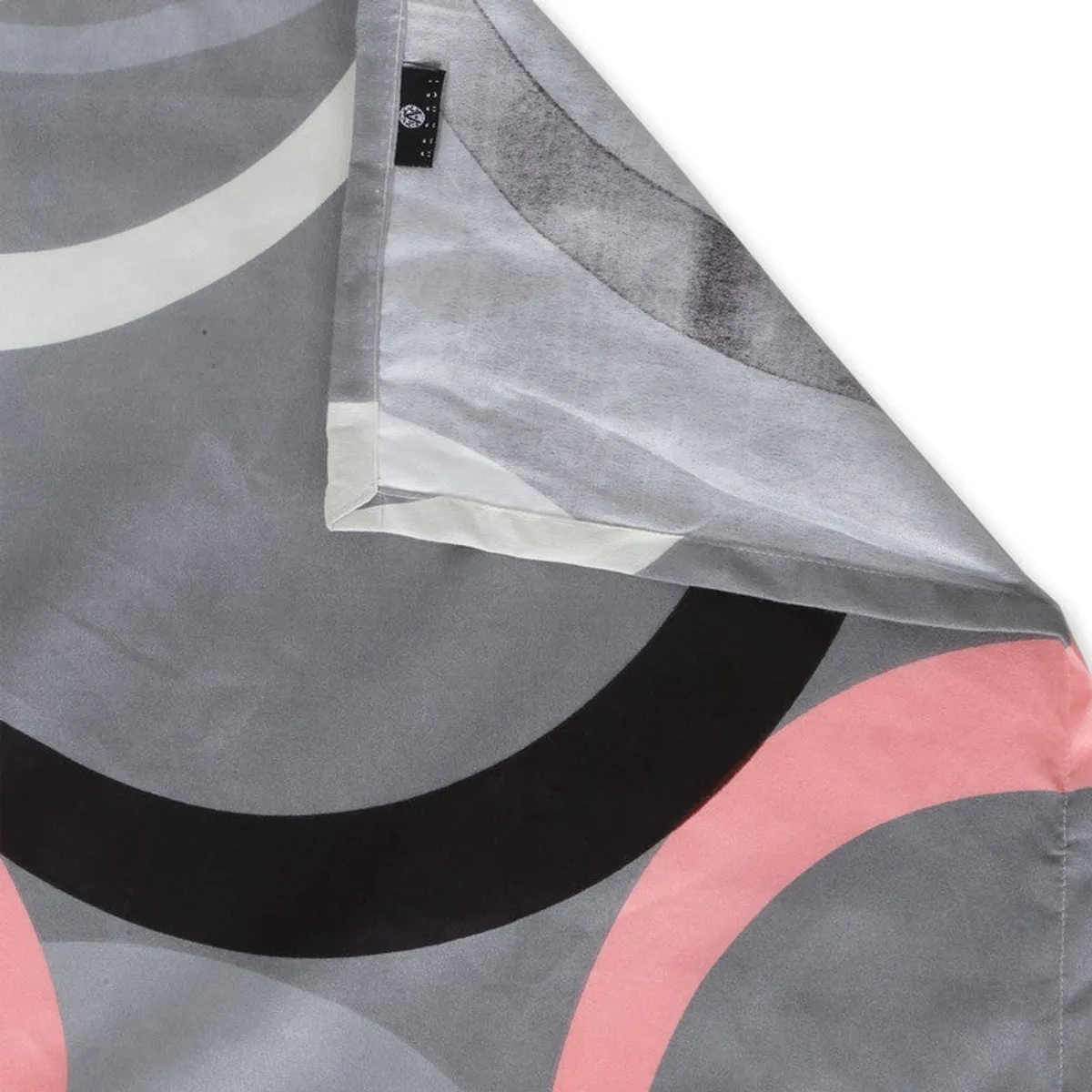 Detailed view of the bedsheet hem and overlapping circular print in grey and pink