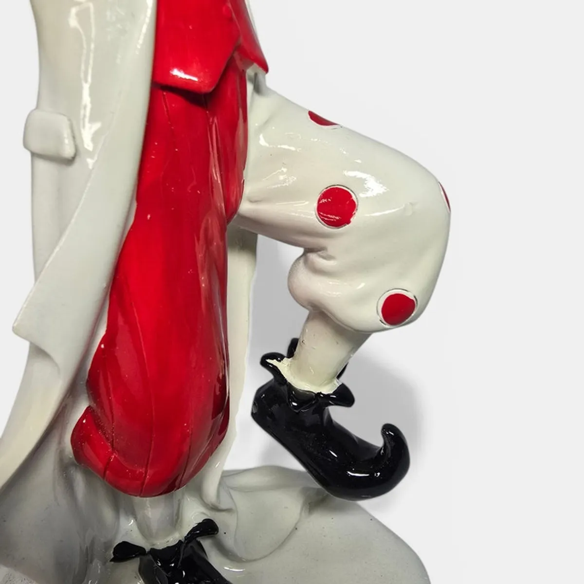 Close-up of clown figurine trousers, coat, and black shoes