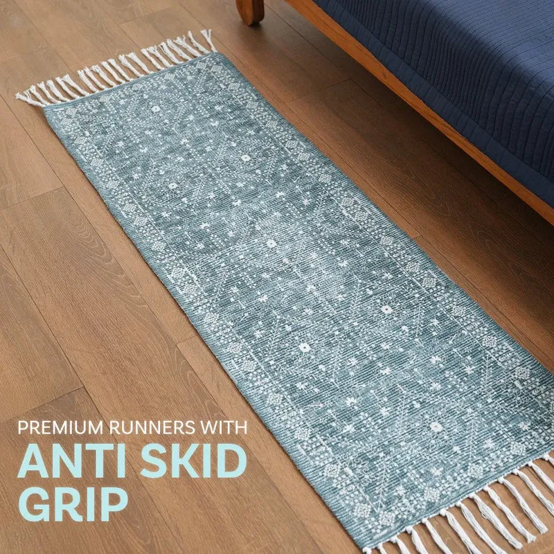 Blue runner rug with fringe placed on wooden floor beside a bed