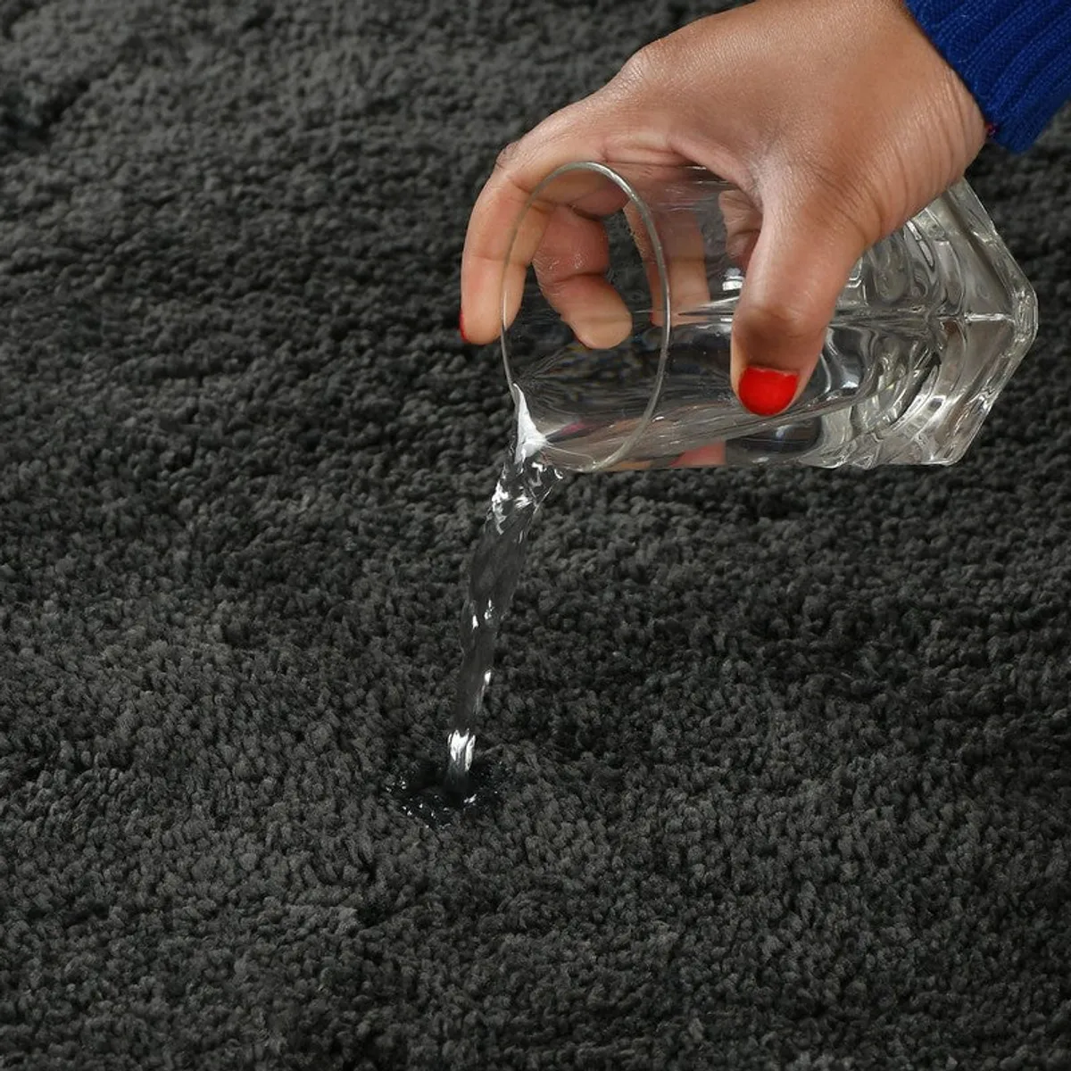 Close-up of water being poured onto a dark textured bath mat