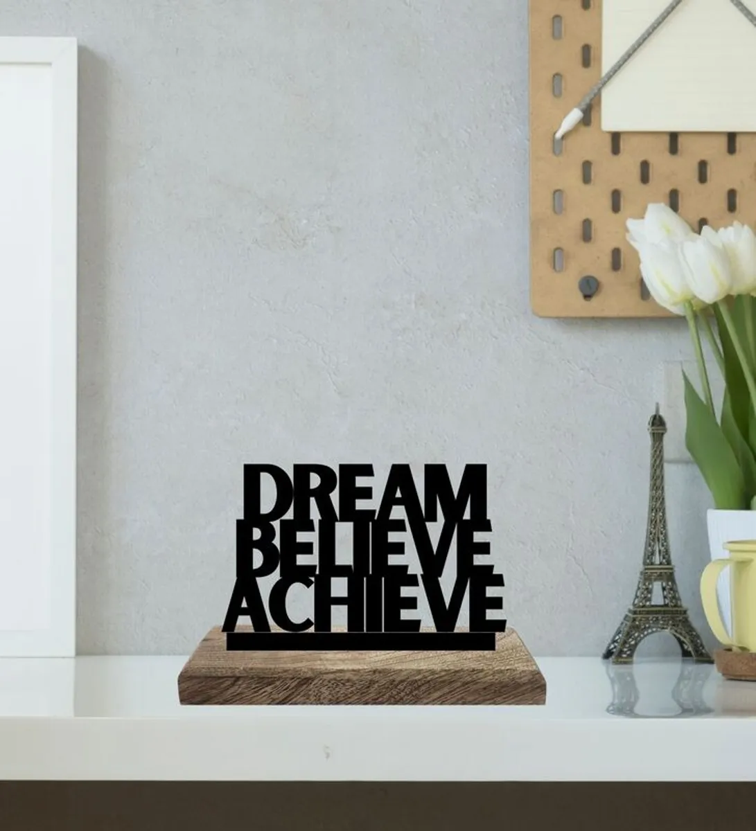Black DREAM BELIEVE ACHIEVE typography showpiece on a wooden base