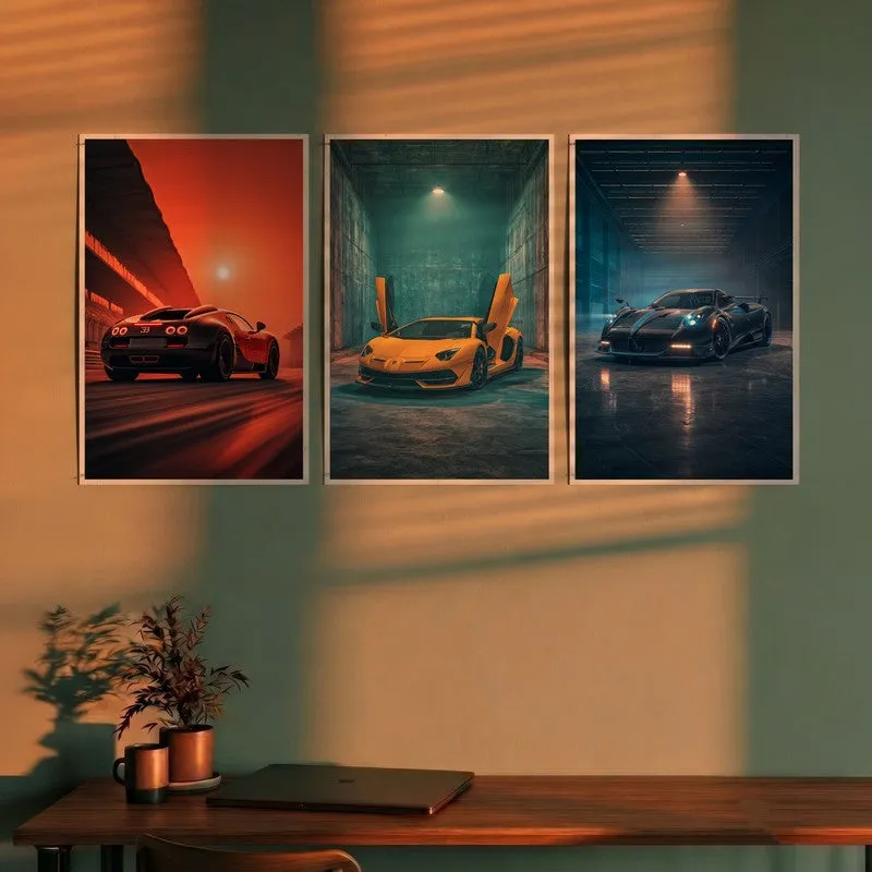 Set of three car wall posters displayed above a wooden desk in warm light
