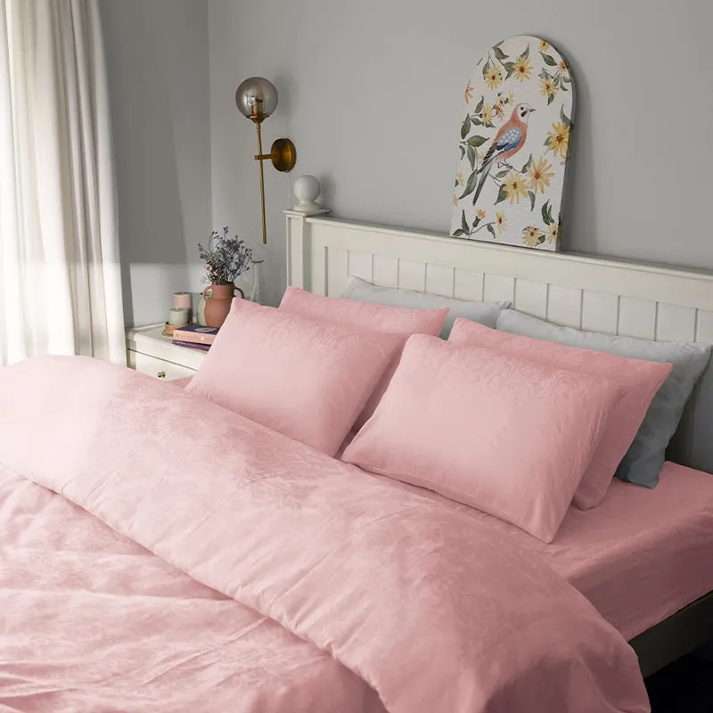 Pink floral duvet cover styled on a white bed in an elegant bedroom.