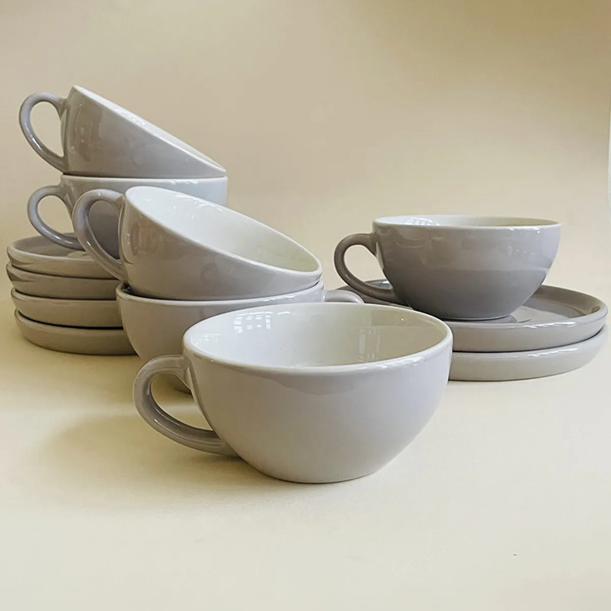 Glossy grey cup and saucers stacked in a relaxed tabletop arrangement