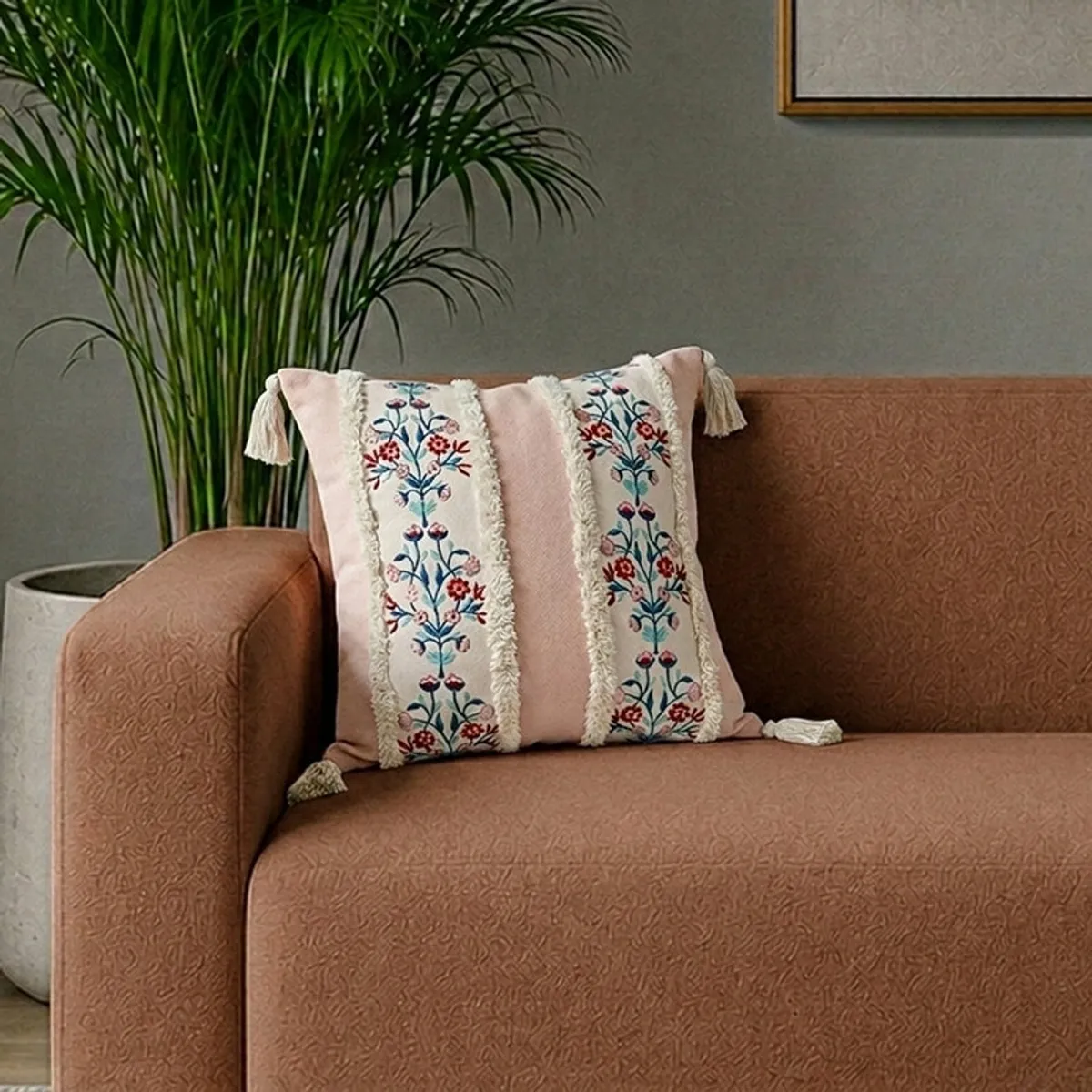 Pink floral embroidered cushion cover styled on a contemporary sofa