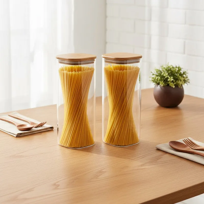 Two transparent glass jars with bamboo lids filled with spaghetti on a wooden table
