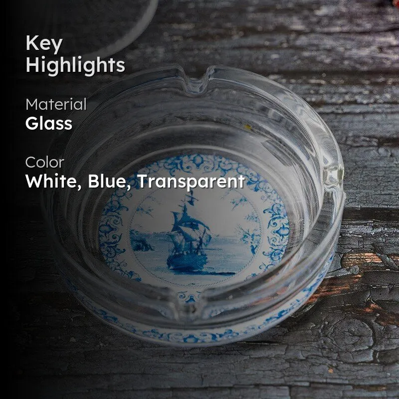 Clear round glass ashtray with blue ship motif on dark wooden surface