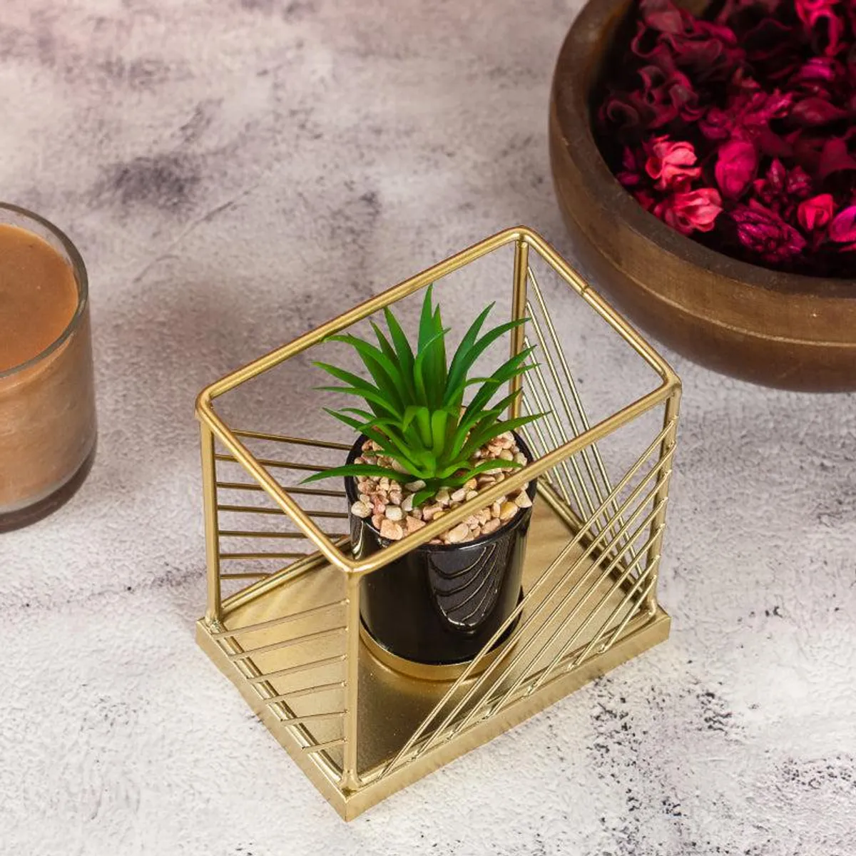 Angled top view of gold geometric planter with black pot, faux plant and pebbles