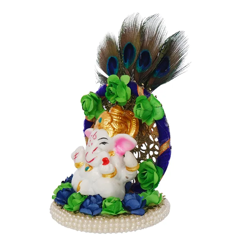 Side angle of a decorated Ganesha idol with peacock feathers and floral accents
