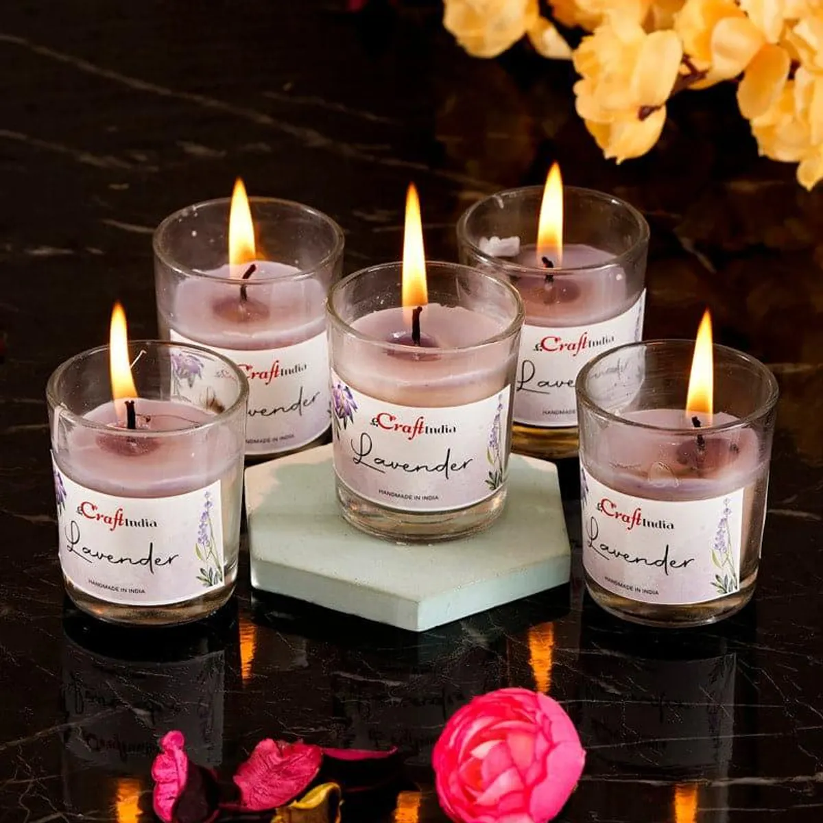 Five purple lavender-scented votive candles in clear glass holders with flames