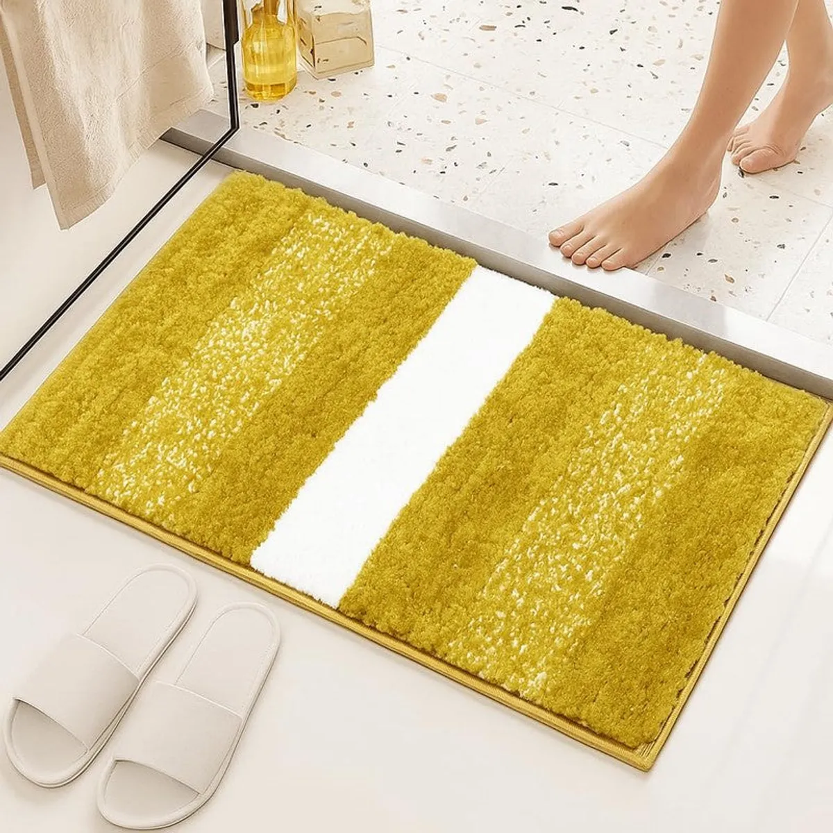 Yellow rectangular bath mat with white centre stripe beside a shower area