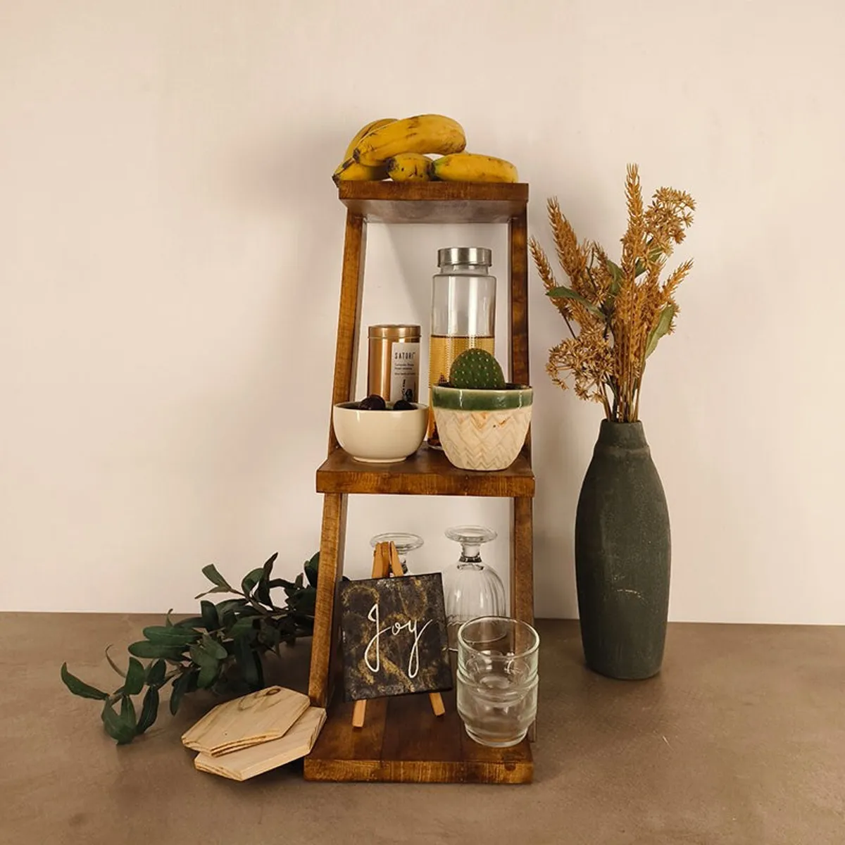 Front view of brown three-tier wooden rack styled with decor