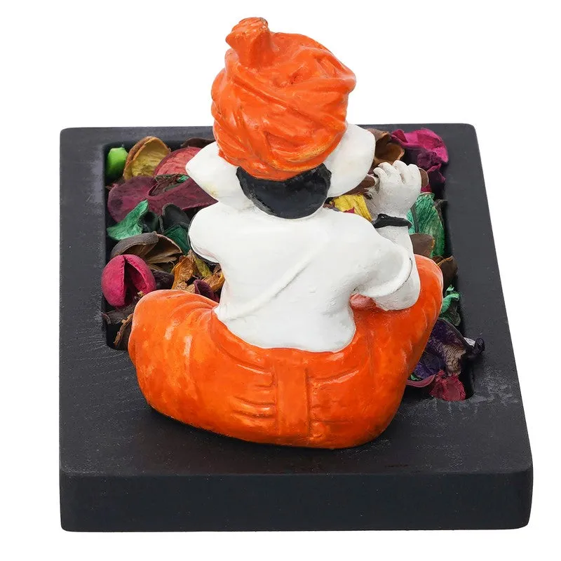 Rear view of orange and white Ganesha figurine on black candle holder base