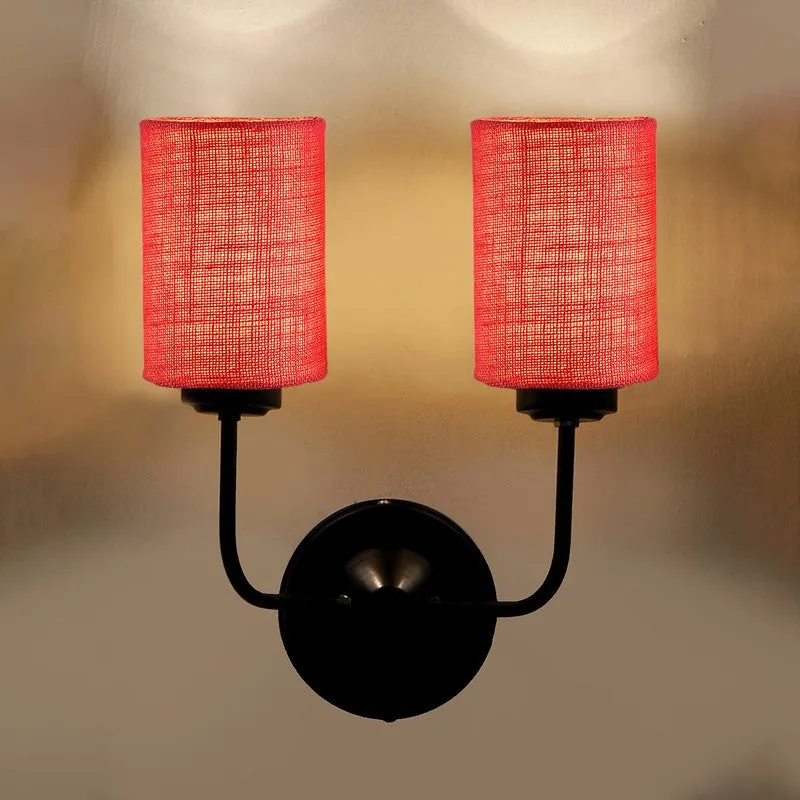 Close view of illuminated pink twin-shade wall lamp on a wall