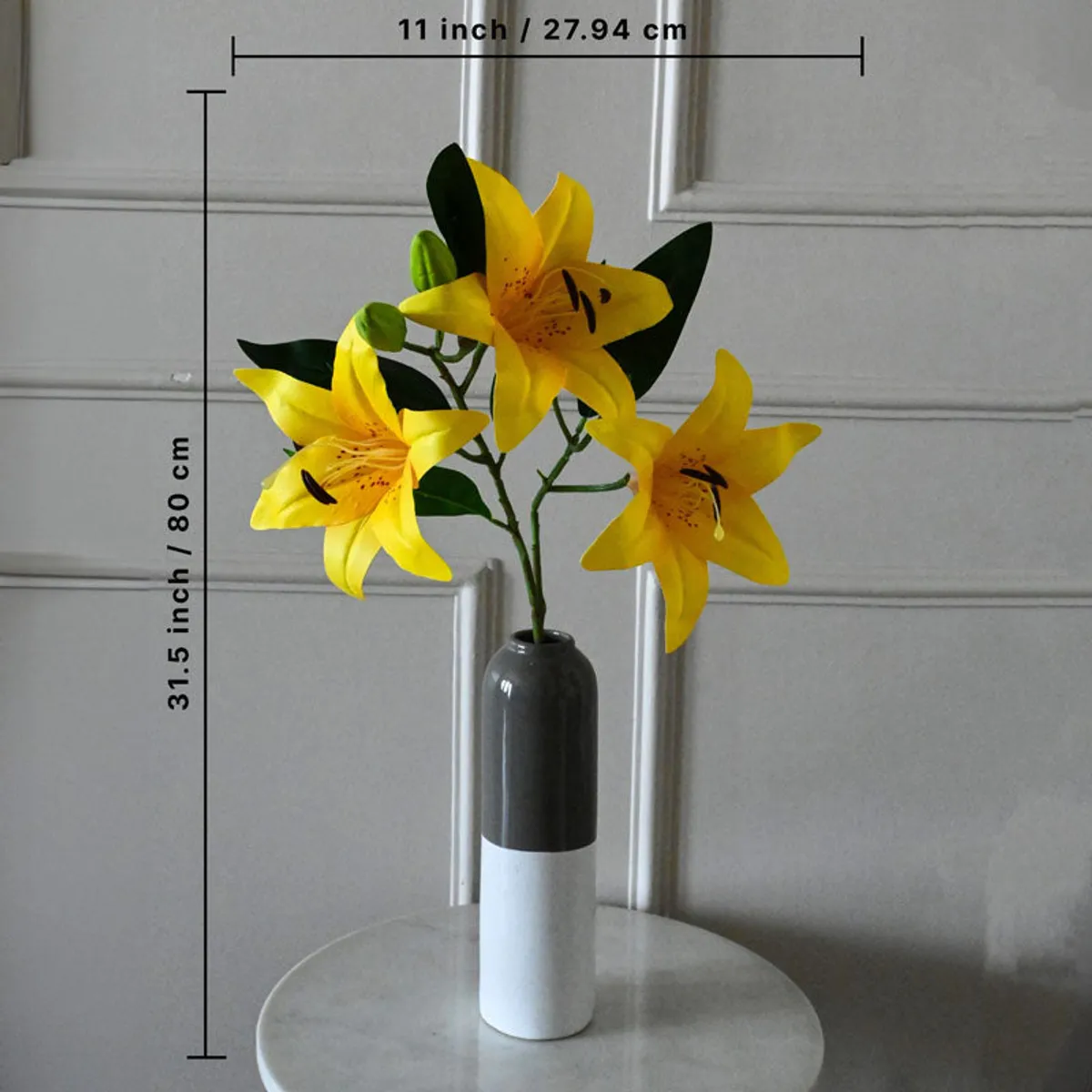 Yellow faux lily flower stick displayed in a vase on a round table