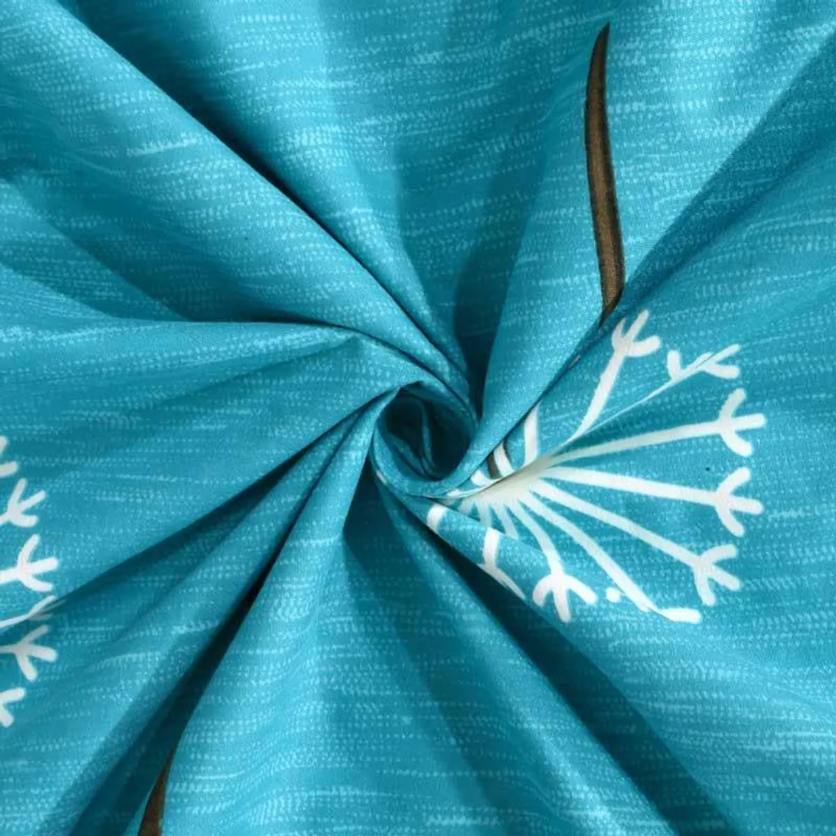 Close-up of the blue printed bedsheet fabric with dandelion detail
