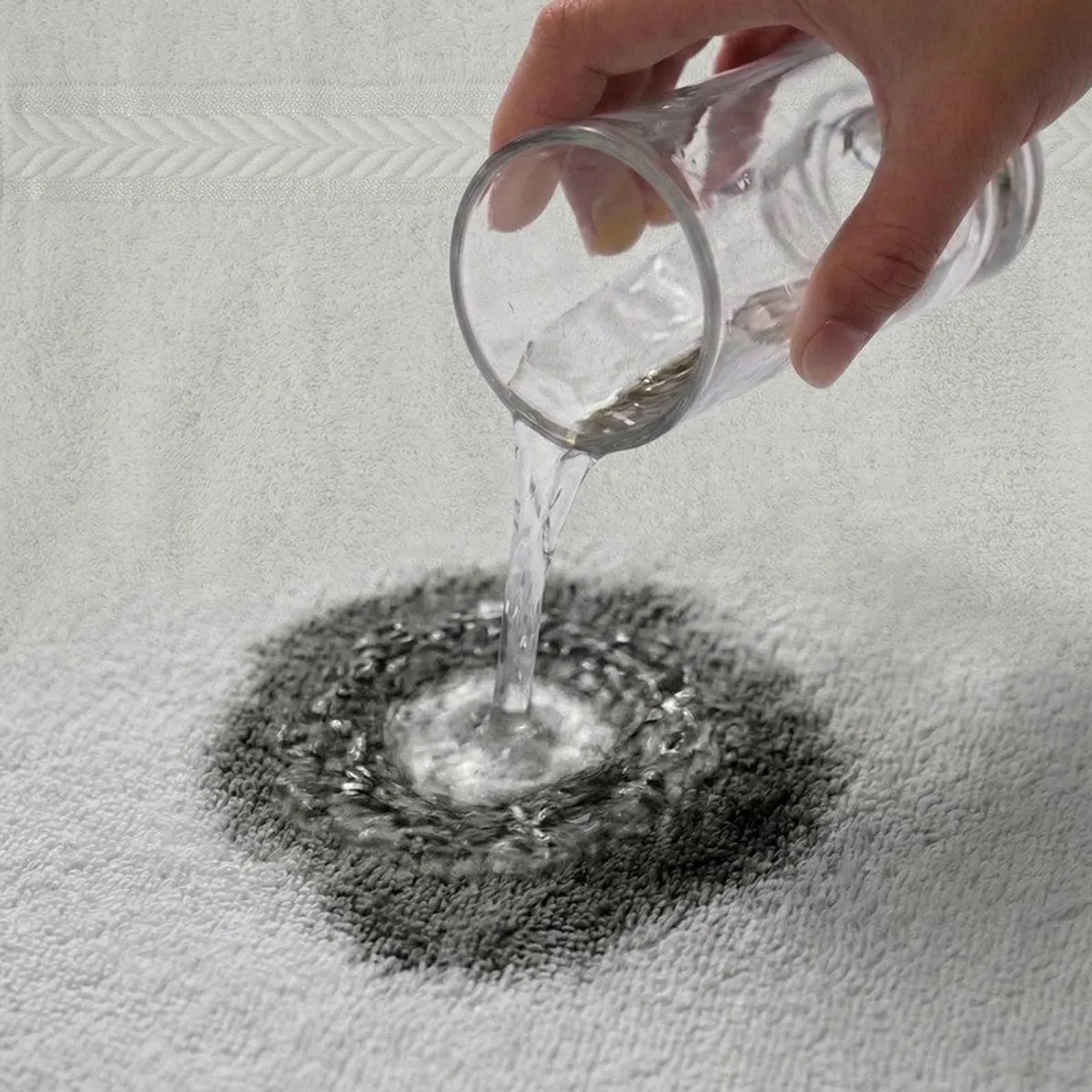 Water being poured onto the absorbent surface of a white towel