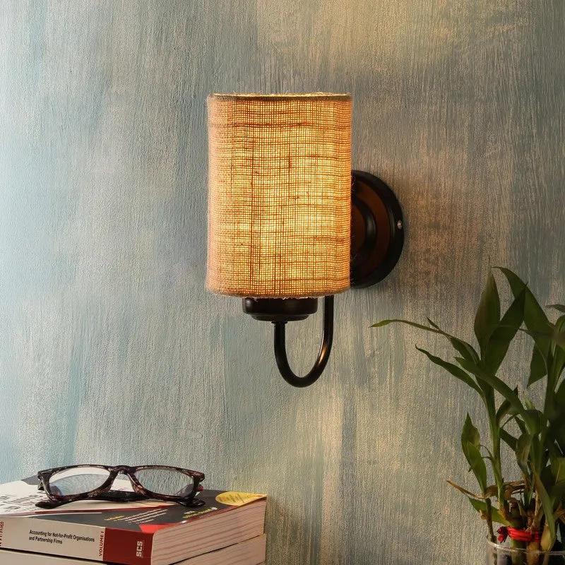 Lit jute wall lamp with black iron base on a textured blue wall