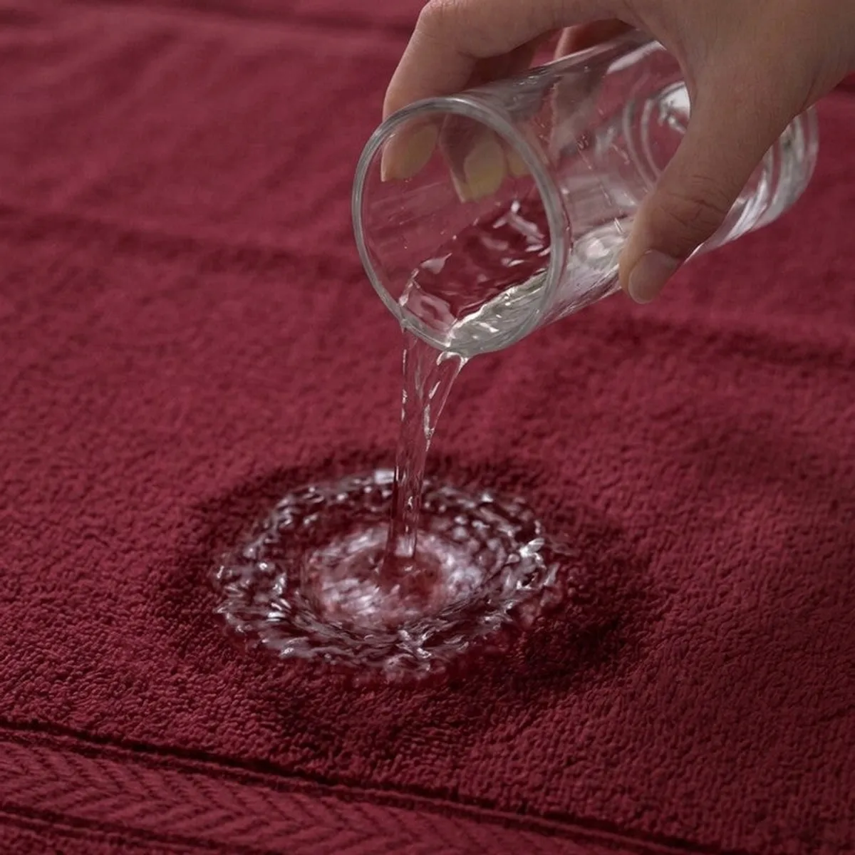 Water soaking into the textured red towel surface