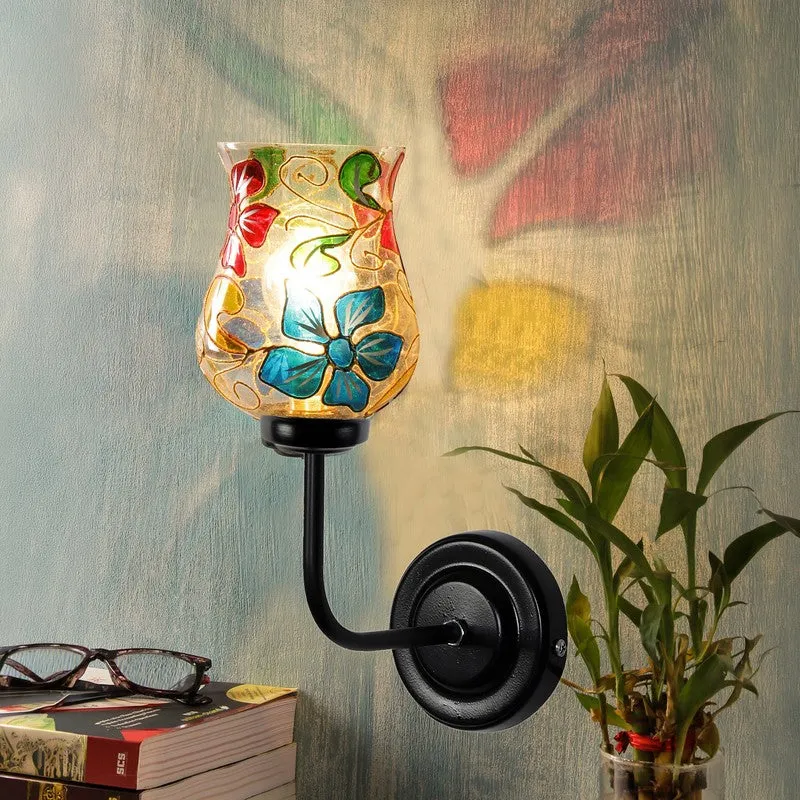 Lit floral glass wall lamp casting colourful reflections on the wall
