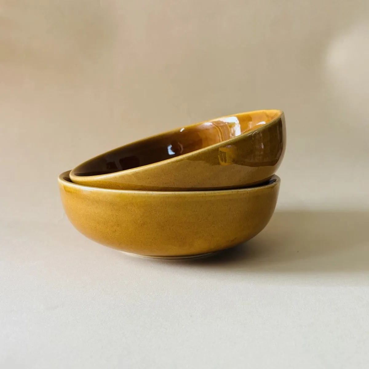 Two brown ceramic serving bowls stacked to show their rounded shape