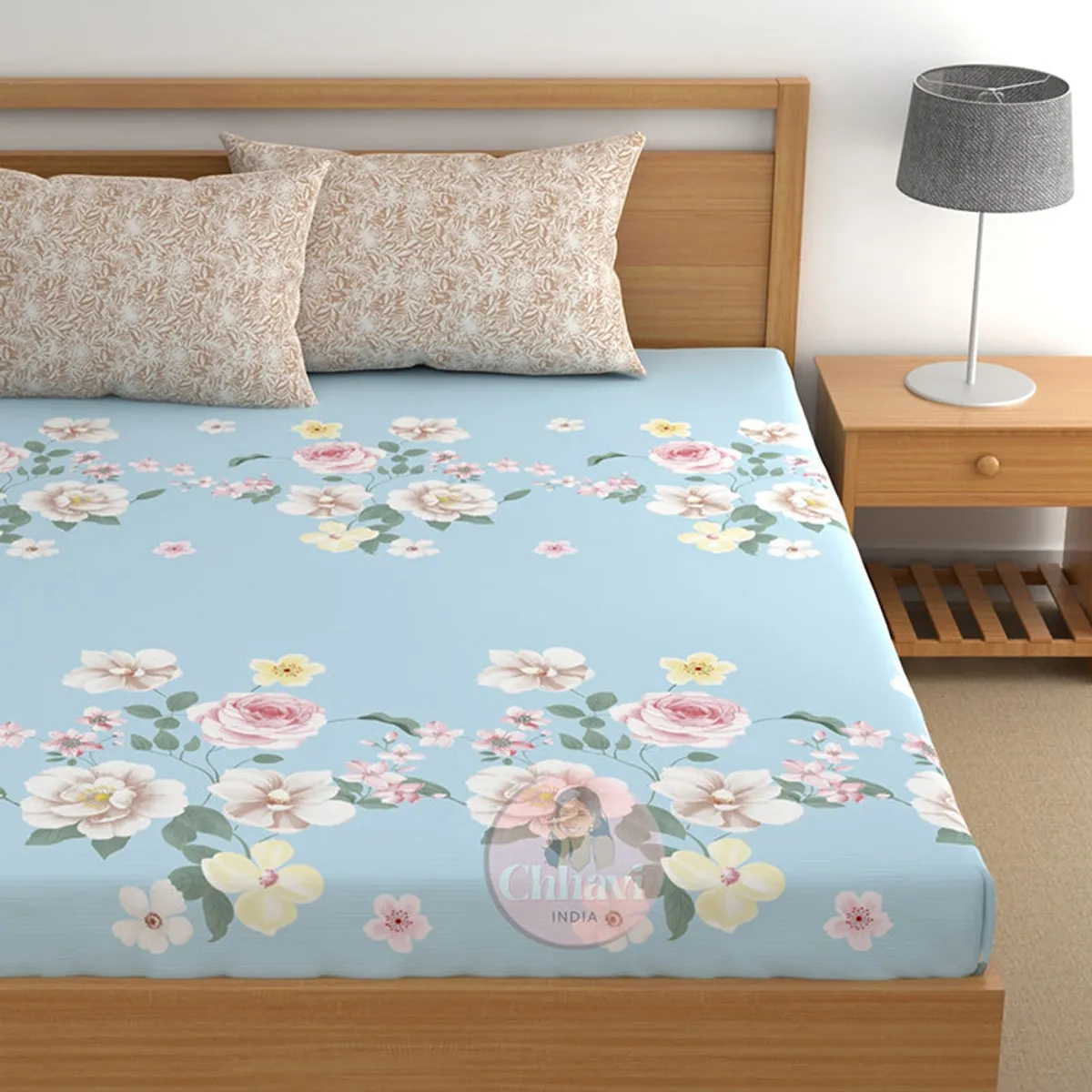 Blue fitted bedsheet with floral border print and two beige pillows