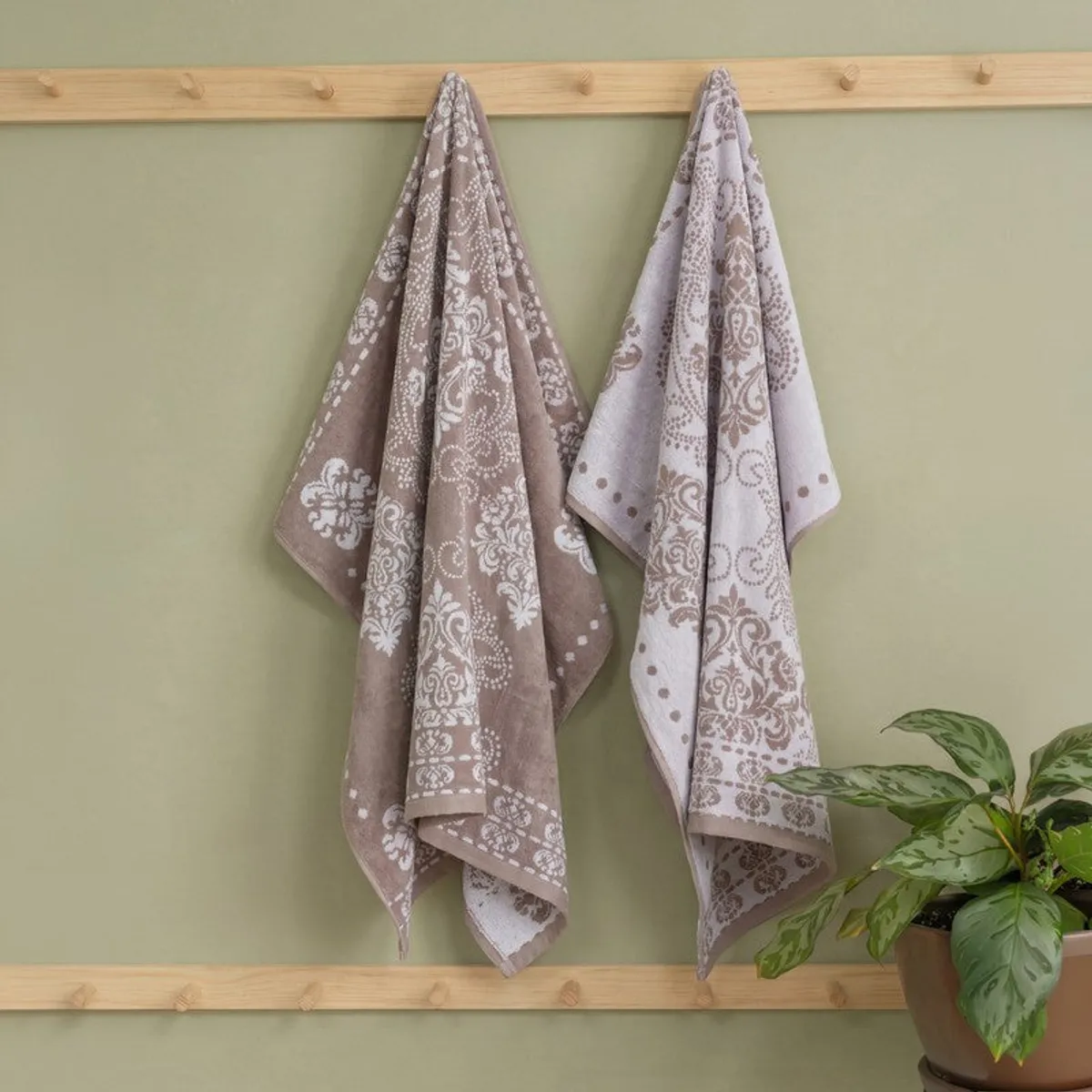 Beige floral bath towel hanging on a wooden wall rack