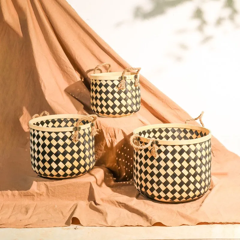 Three black and natural bamboo planters arranged in a sunlit indoor setting.