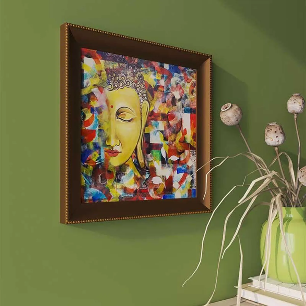 Angled view of square framed Buddha wall art on an olive green wall beside a vase