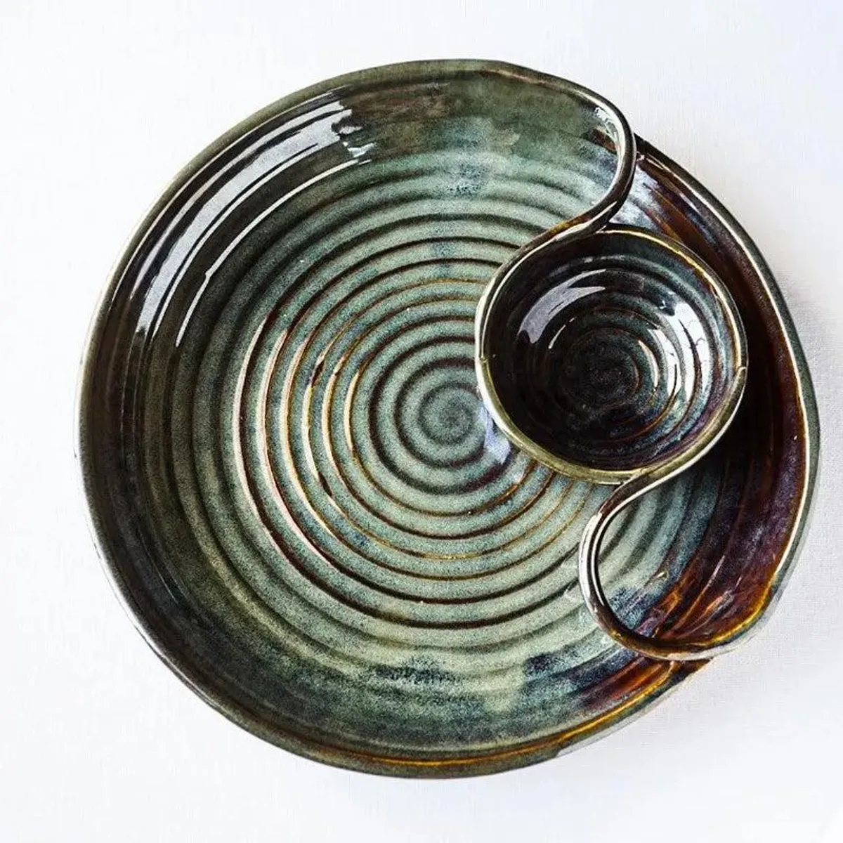 Round glossy deep green ceramic platter with concentric rings and a curved dip section