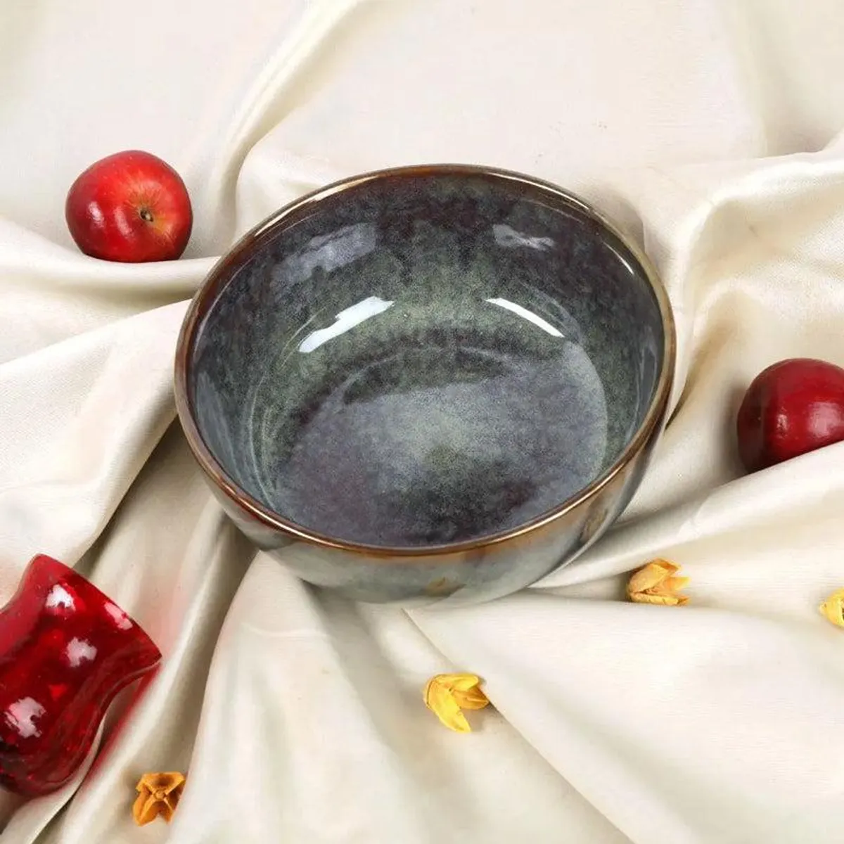 Glossy ceramic serving bowl with dark green and burgundy tones styled with fruit