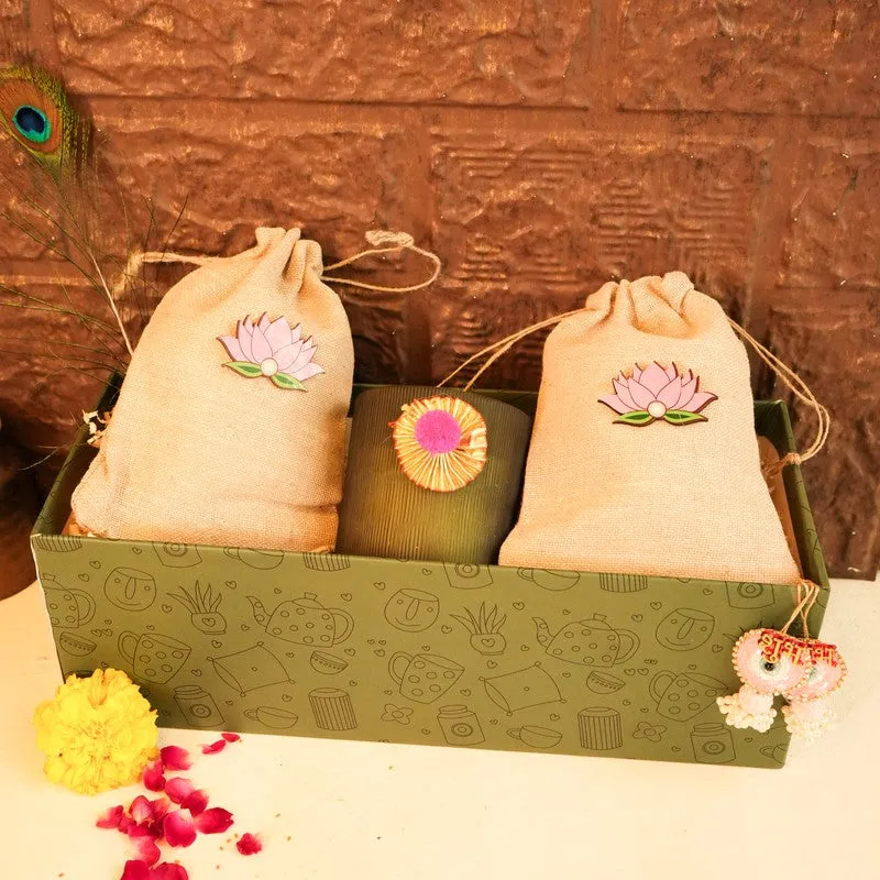 Two lotus potlis and ribbed candle displayed in a patterned green gift box