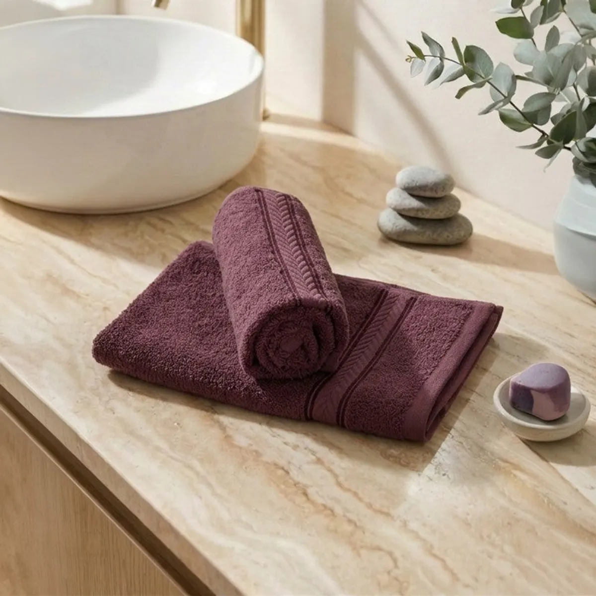 Folded purple hand towels styled beside a basin and spa accessories