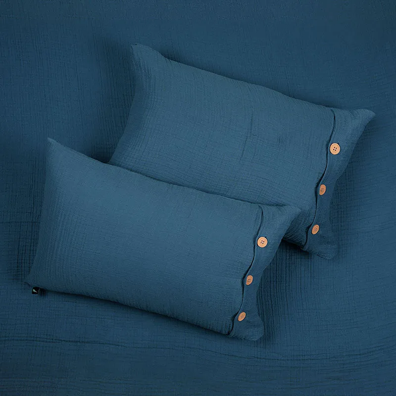 Two navy blue pillow covers with button details arranged on matching bedding