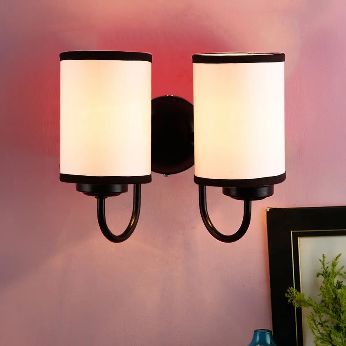 Close view of dual wall lamp with white shades and dark contrast trim