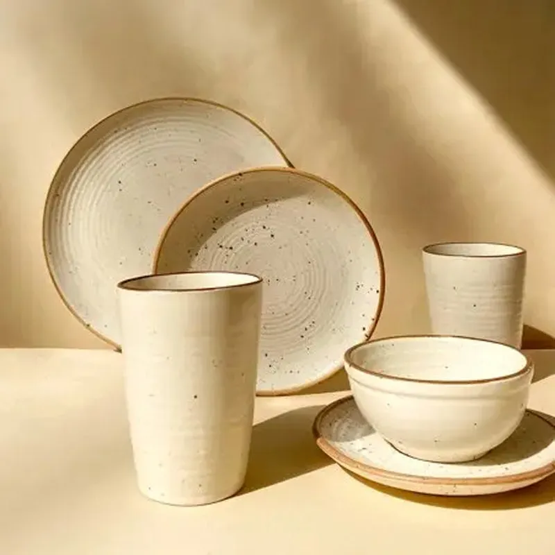 Handmade speckled ceramic dinnerware in warm white with plates, bowls and tumblers